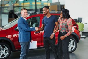 Couple buying a red car from salesman