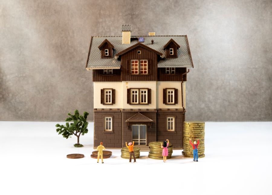 Model house with miniature people and coin stacks.