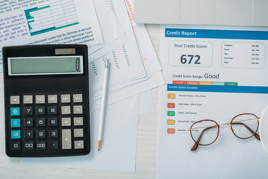 Calculator, credit report, and glasses on desk.