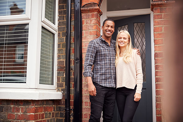 Couple smiling in front of their home
